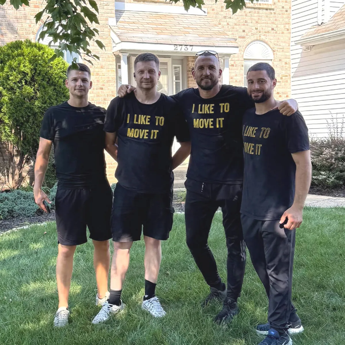 Four CarePhilly movers in company shirts outside a house