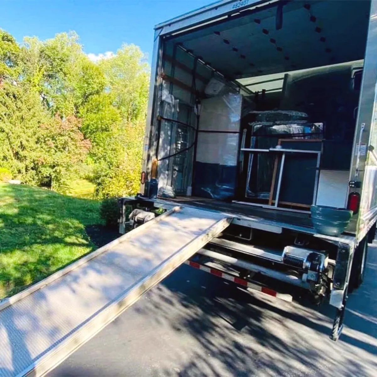 The truck ramp lowered at a house, the load strapped inside